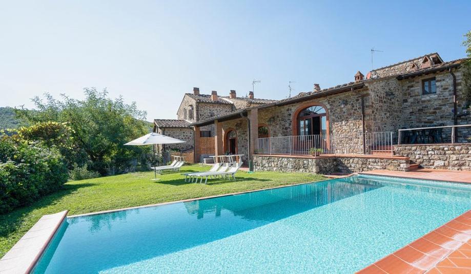 a villa with a swimming pool in front of a house at Le Masse in Greve in Chianti