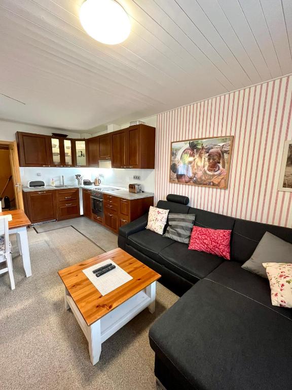 a living room with a black couch and a table at Apartmán C01 Poustevník in Pec pod Sněžkou