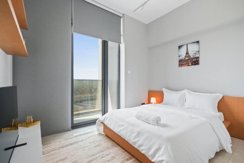 Dormitorio blanco con cama y ventana grande en Peaceful Studio - Wpool - Gym en Dubái