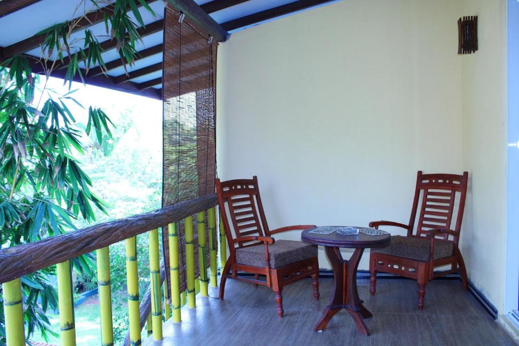 un portico con 2 sedie e un tavolo sul balcone di Raj Mahal Inn a Wadduwa