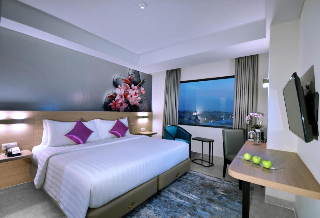 ein Hotelzimmer mit einem großen Bett und einem Fenster in der Unterkunft Quest Prime Cikarang by ASTON in Bekasi