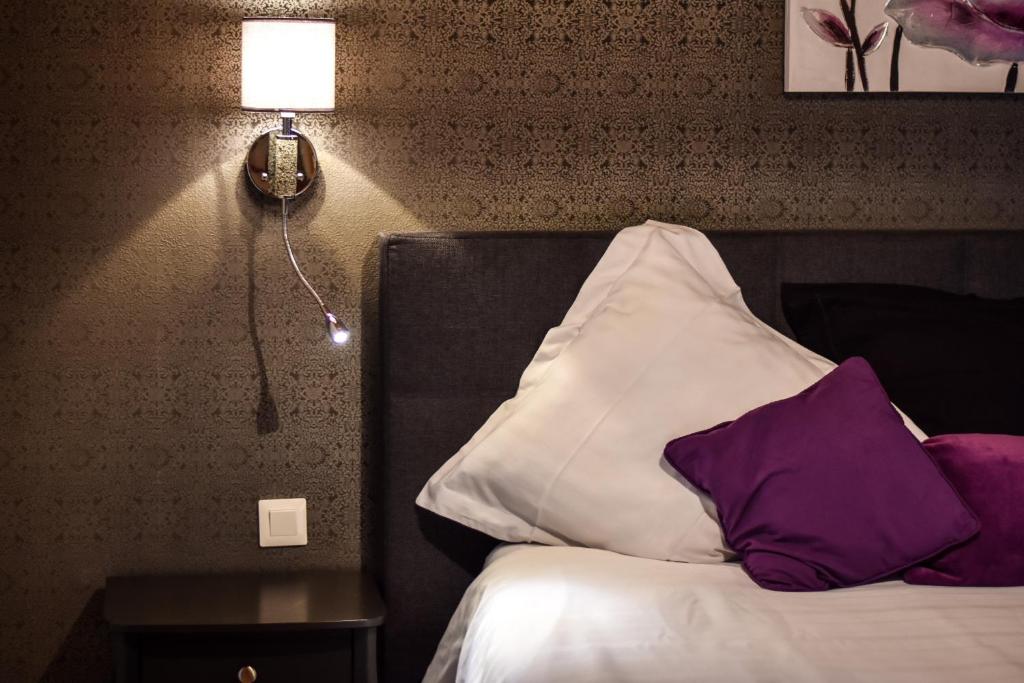 1 dormitorio con 1 cama con almohadas moradas y blancas en Gite Clos Angélique, en Hazelbourg