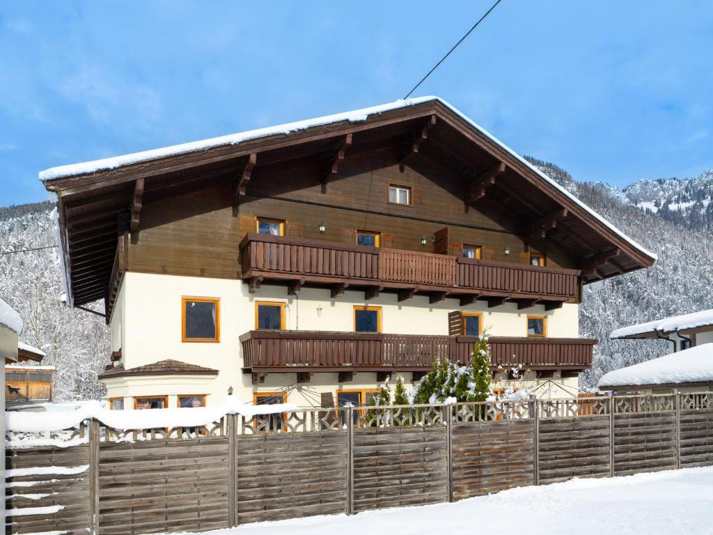 una casa con una valla de madera en la nieve en Haus Alpenrose, en Waidring