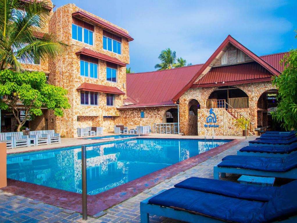 una piscina del complejo con tumbonas frente a un edificio en Serene Beach Resort en Dar es Salaam