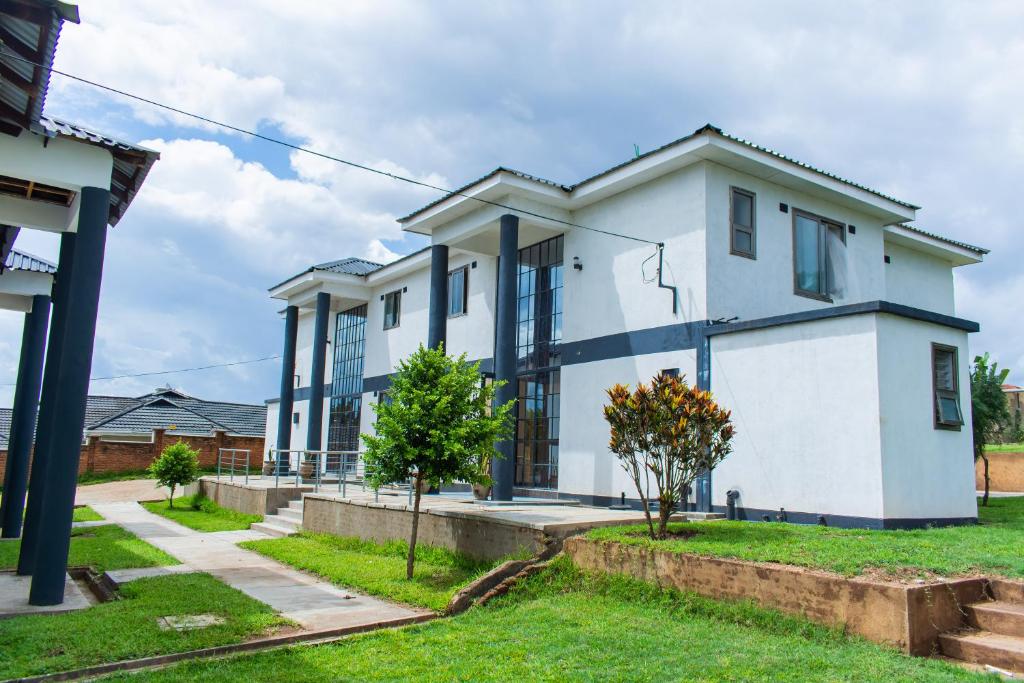 ein weißes Haus mit Fenstern und Gras in der Unterkunft Divine Heights Apartments Lilongwe Area 43 in Lilongwe