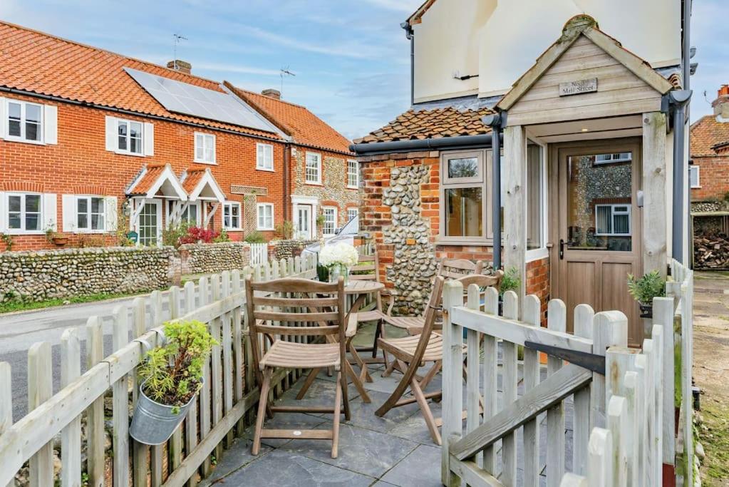 a patio with a wooden fence and a table and chairs at 3 Mill Street - Norfolk Cottage Agency in Holt