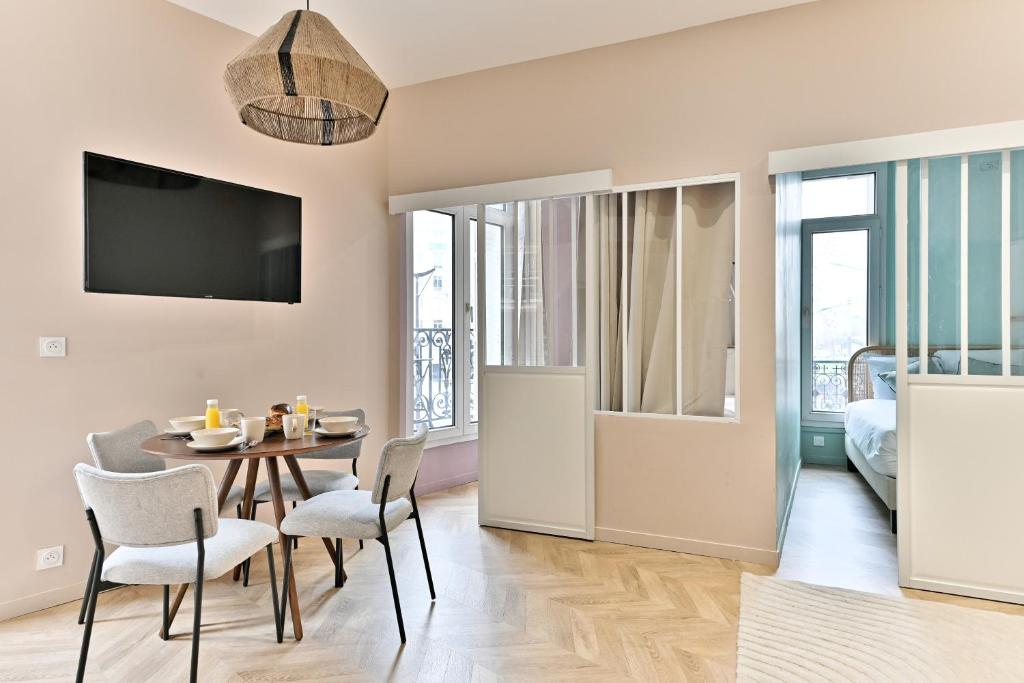 - une salle à manger avec une table, des chaises et une télévision dans l'établissement Appartement proche Parc Monceau - II, à Paris