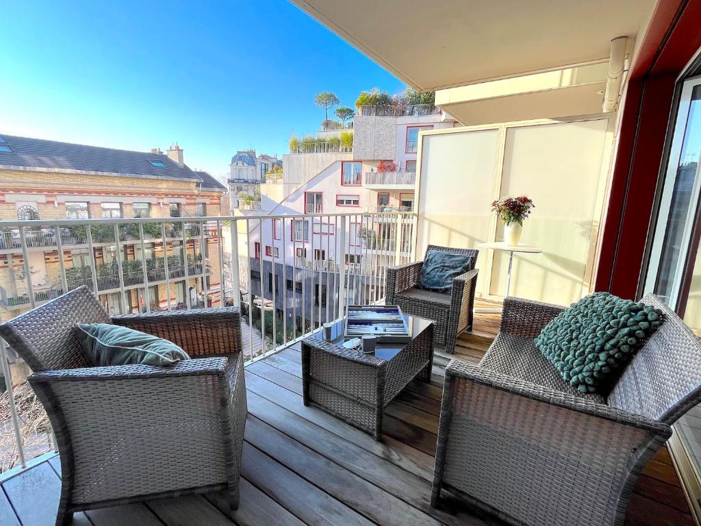 - un balcon avec des chaises en osier et une table dans un bâtiment dans l'établissement le Penthouse des Batignolles, à Paris