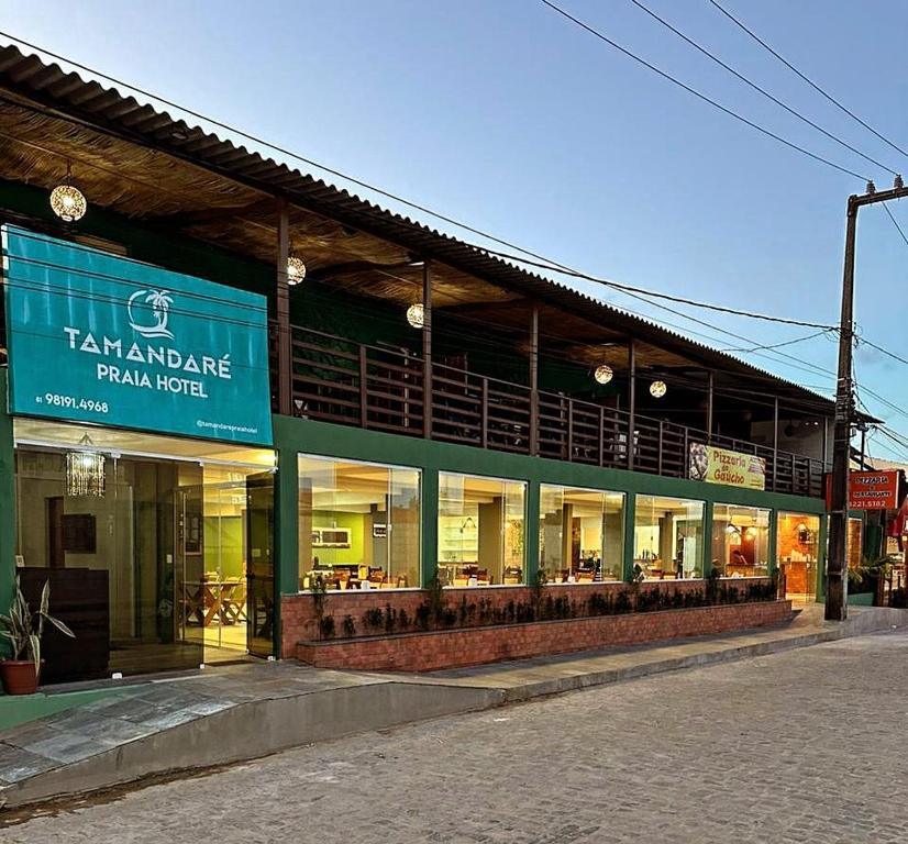 um grande edifício com uma pizzaria numa rua em Tamandaré Praia Hotel em Tamandaré