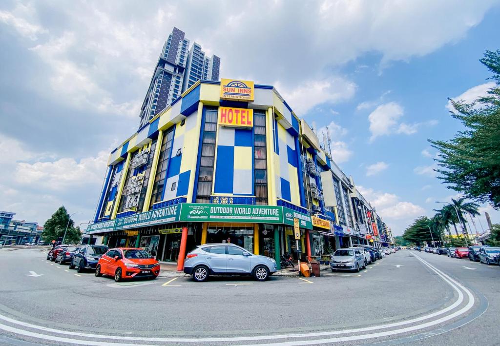 Sun Inns D2 @ Seri Kembangan في سيري كيمبانغان: مبنى كبير به سيارات تقف في موقف للسيارات