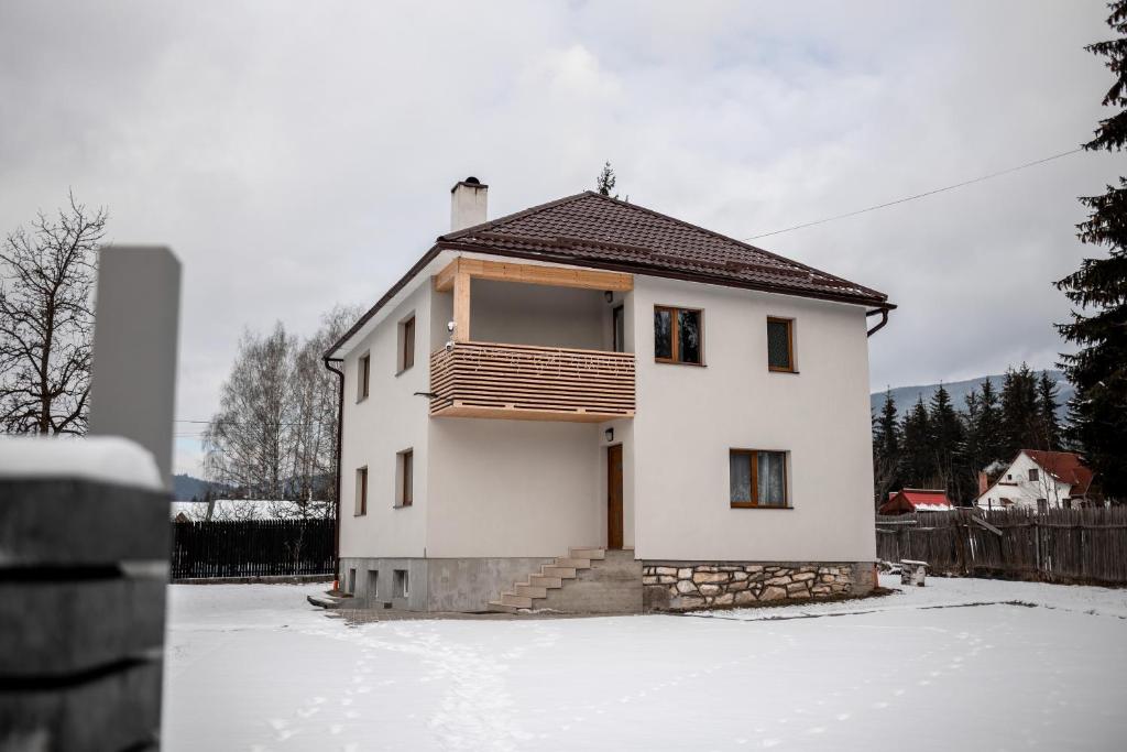 a white house with a balcony in the snow at Casa Tinca 1 in Izvoru Mureşului