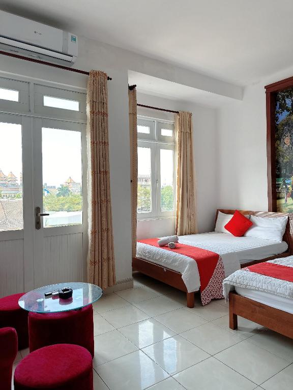 a room with two beds and a table and windows at GOLDEN TWO Hotel in Vung Tau