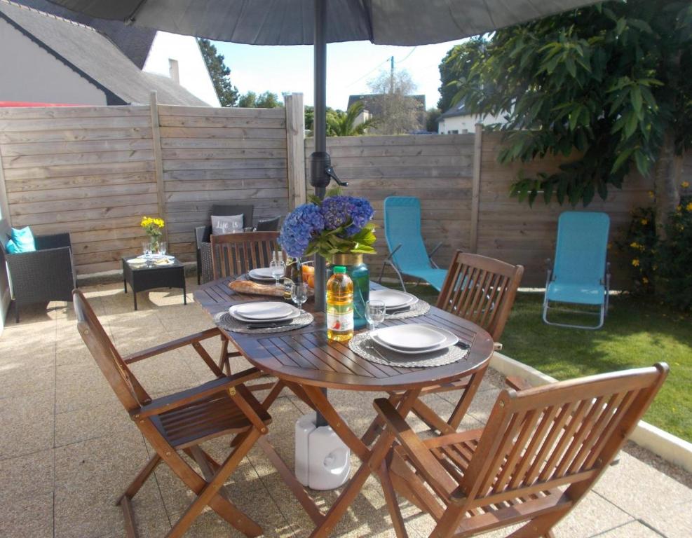 un tavolo in legno con sedie e un ombrellone su un patio di Les hortensias a Louannec