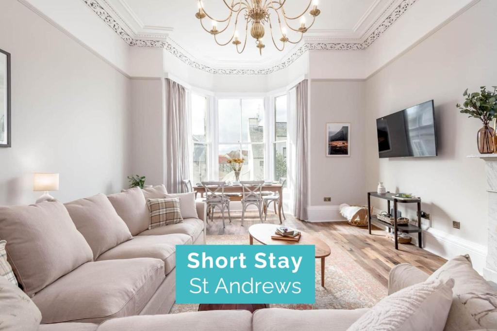 a living room with a couch and a chandelier at Skye Sands - 11 Alexandra Penthouse - St Andrews in St Andrews