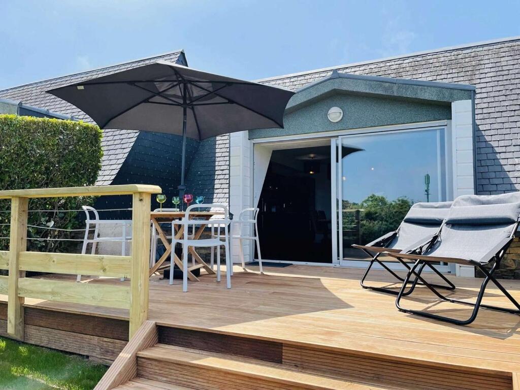 un patio avec un parasol et des chaises sur une terrasse dans l'établissement La terrasse sur le golf, à Pleumeur-Bodou