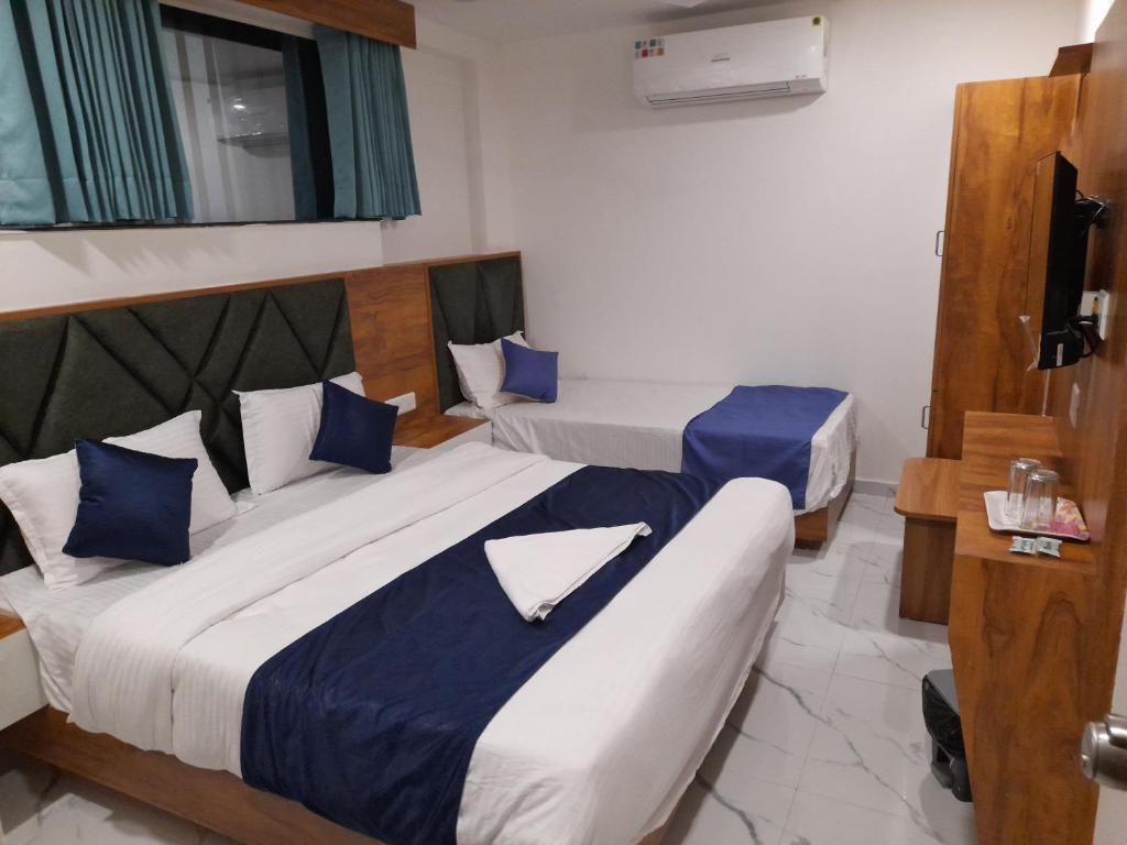 Habitación de hotel con 2 camas y almohadas azules en Hotel Era en Ahmedabad