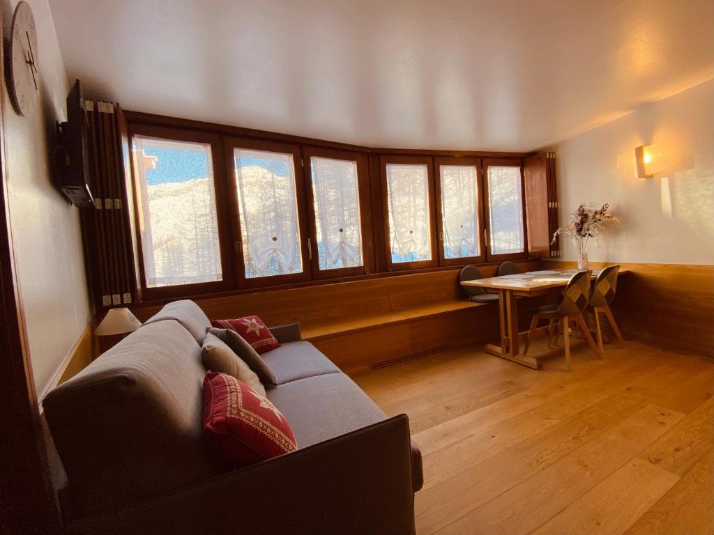 een woonkamer met een bank, een tafel en ramen bij Charlotte Lodge Cervinia in Breuil-Cervinia