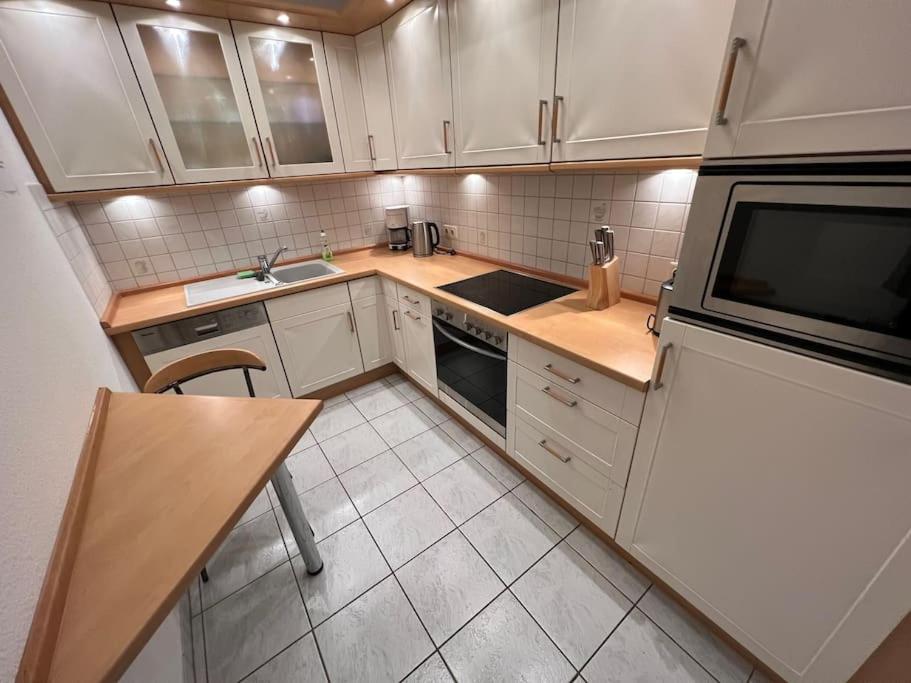 a kitchen with white cabinets and a table and a microwave at Wiehengebirgs Fernblick App 2 in Bad Essen