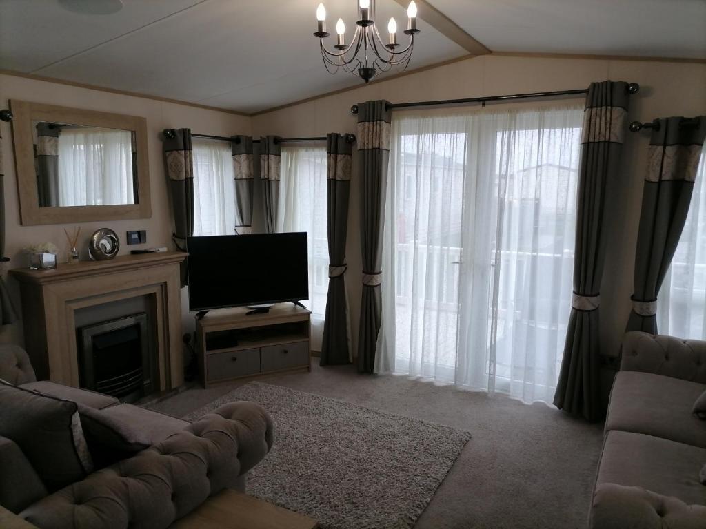a living room with a couch and a television at Alberta Holiday Park in Seasalter