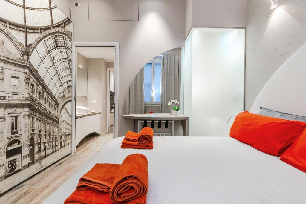 - une chambre avec un grand lit blanc et des oreillers orange dans l'établissement [DUOMO 14 min] Orange Milano M3, à Milan