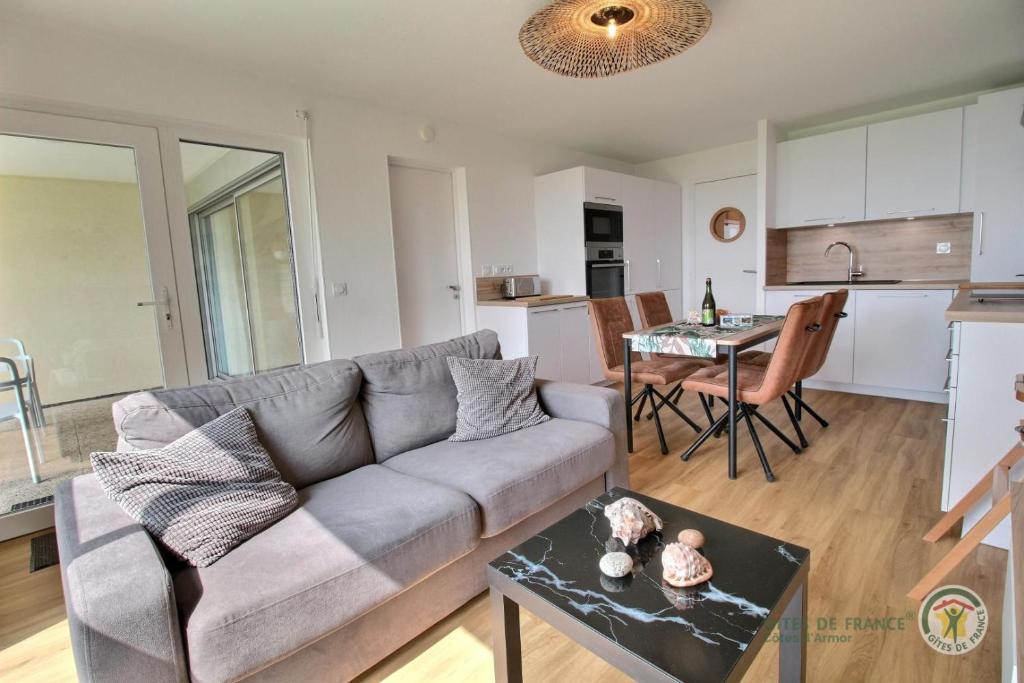 a living room with a couch and a table at La plage in Trébeurden