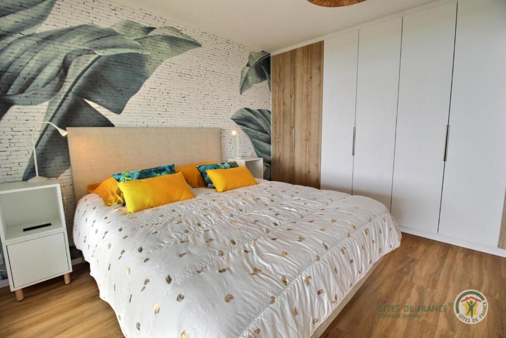 a bedroom with a large white bed with yellow pillows at La plage in Trébeurden