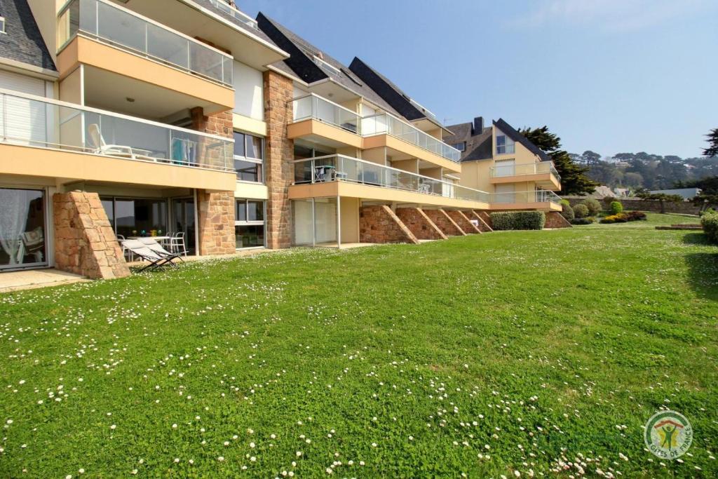 a large grassy yard in front of a building at La plage in Trébeurden