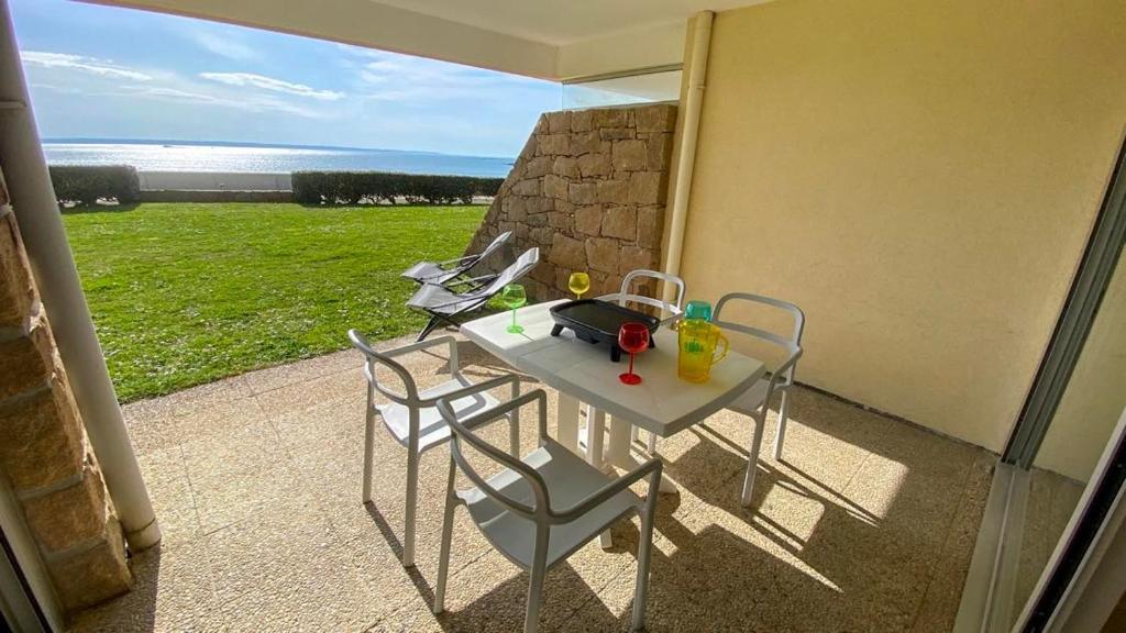 a table and chairs on a balcony with a view of the ocean at La plage in Trébeurden