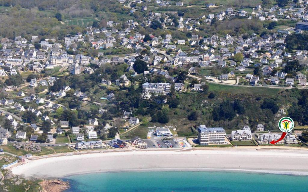 a kite flying over a beach next to the ocean at La plage in Trébeurden