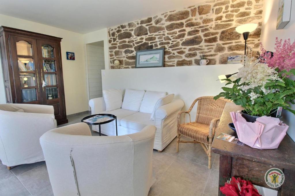 a living room with white furniture and a stone wall at Ipanema in Trébeurden
