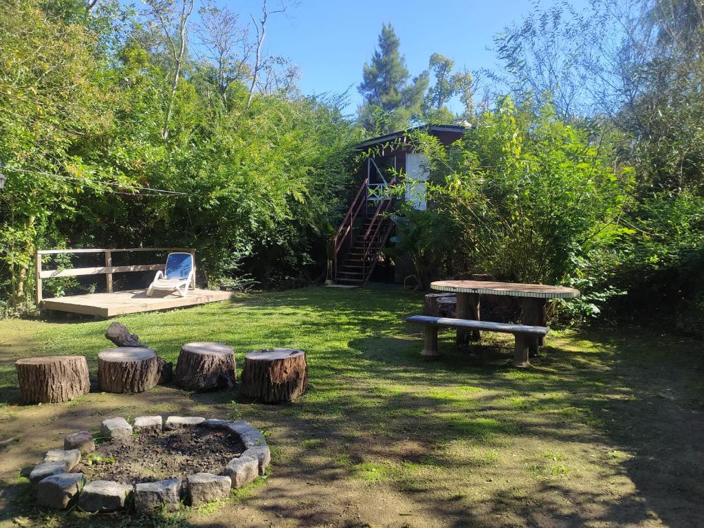 un parc avec un banc et des bûches dans l'herbe dans l'établissement Cabaña enero soleado, à Tigre