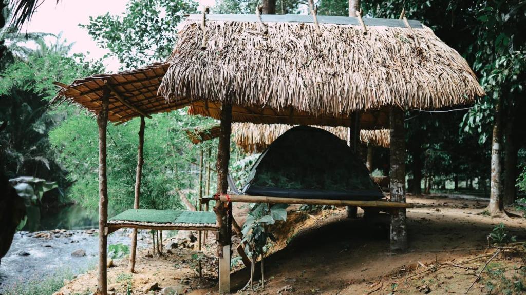 Cabaña de paja con silla y mesa en สวนบุศรา ลานกางเต็นท์วิถีเกษตร, en Ban Bok Fai