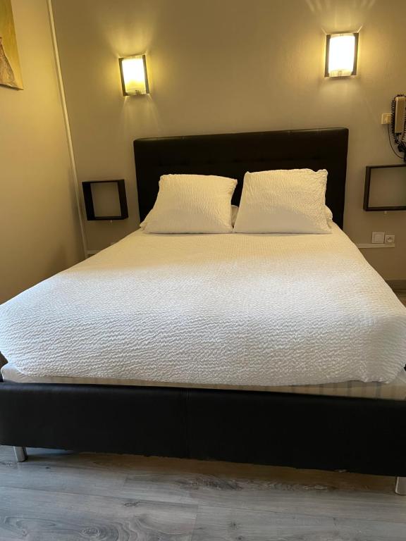 Elle comprend un grand lit avec des draps blancs et 2 oreillers. dans l&#39;établissement Logis Hôtel Le Clement V, à Roquemaure