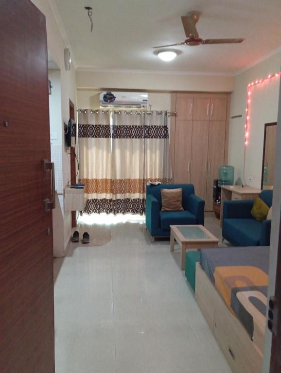 a living room with blue chairs and a couch at Home Stay 1 in Noida