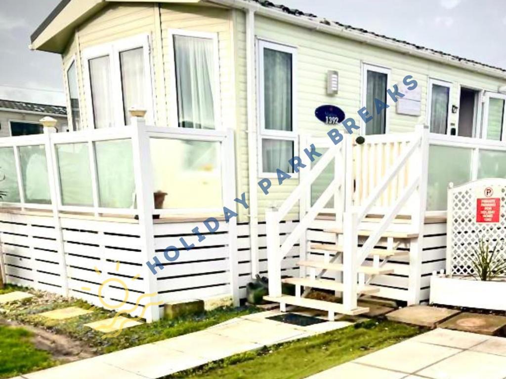 uma cerca branca em frente a uma casa em Marlow - Gold 2 bed with veranda and parking at Seal Bay Resort em Selsey