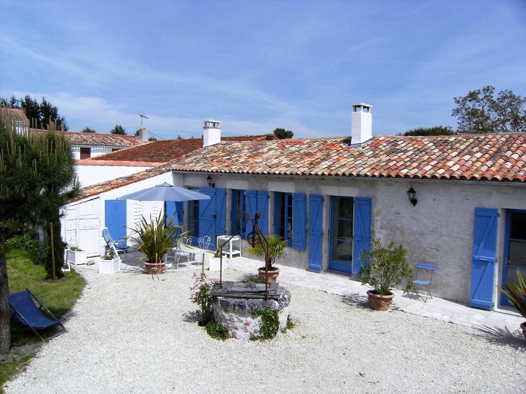 ein weißes Haus mit blauen Türen und einem Hof in der Unterkunft Les Mathes La Palmyre - MAISON CHARENTAISE DE CHARME - CALME -CAMPAGNE in Les Mathes