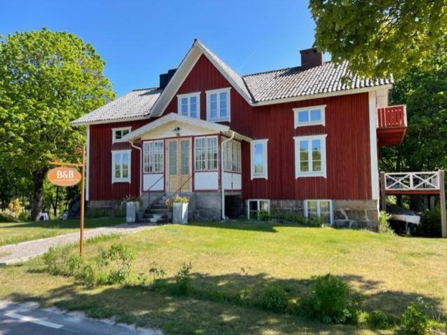 a red house with a sign in front of it at Hollands Län in Unnaryd