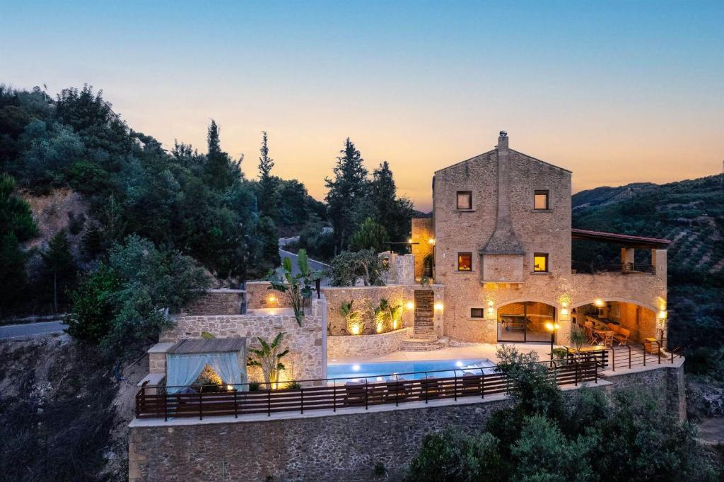 Una gran casa de piedra con una piscina en la parte delantera en Kotinos Luxury Villa, en La Canea