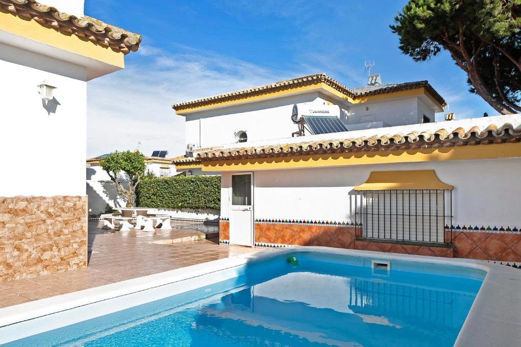 uma villa com piscina em frente a uma casa em Chalet con Piscina y Barbacoa 4 d em Chiclana de la Frontera