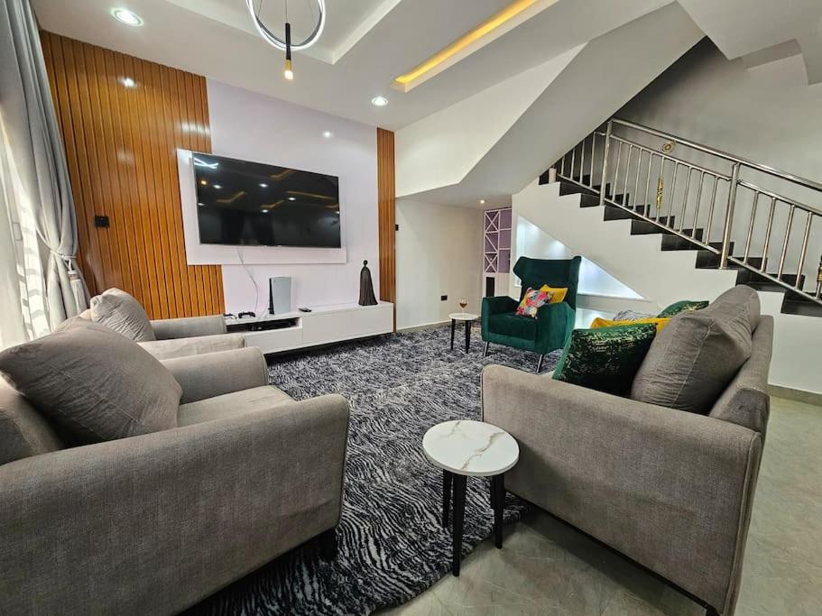 een woonkamer met 2 banken en een trap bij Grey Villa - 3 bedroom Duplex in Abuja