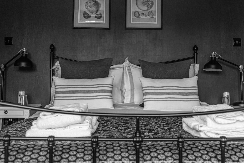 ein schwarz-weißes Foto eines Bettes mit Kissen in der Unterkunft Saltmarsh Farmhouse in West Dean