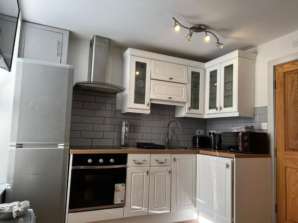 a kitchen with white cabinets and a stove top oven at One Bed Rylands Street in Warrington