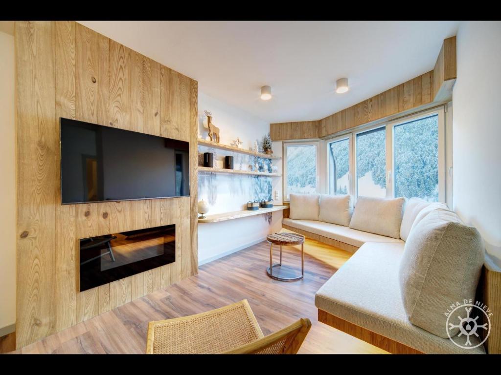 sala de estar con sofá, TV y chimenea en COLOMERS de Alma de Nieve, en Naut Aran (Alto Arán)