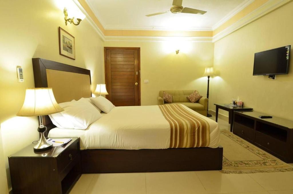 een hotelkamer met een bed en een televisie bij Pak Continental Hotel in Bahawalpur