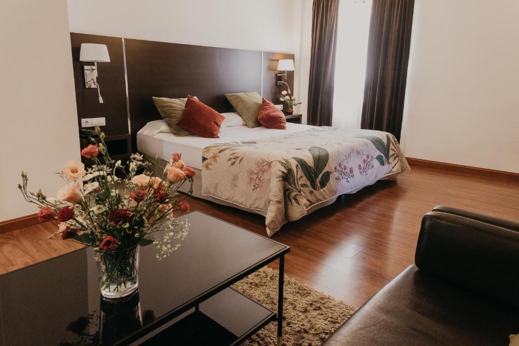 a bedroom with a bed and a table with a vase of flowers at Mare Hotel in Dos Hermanas