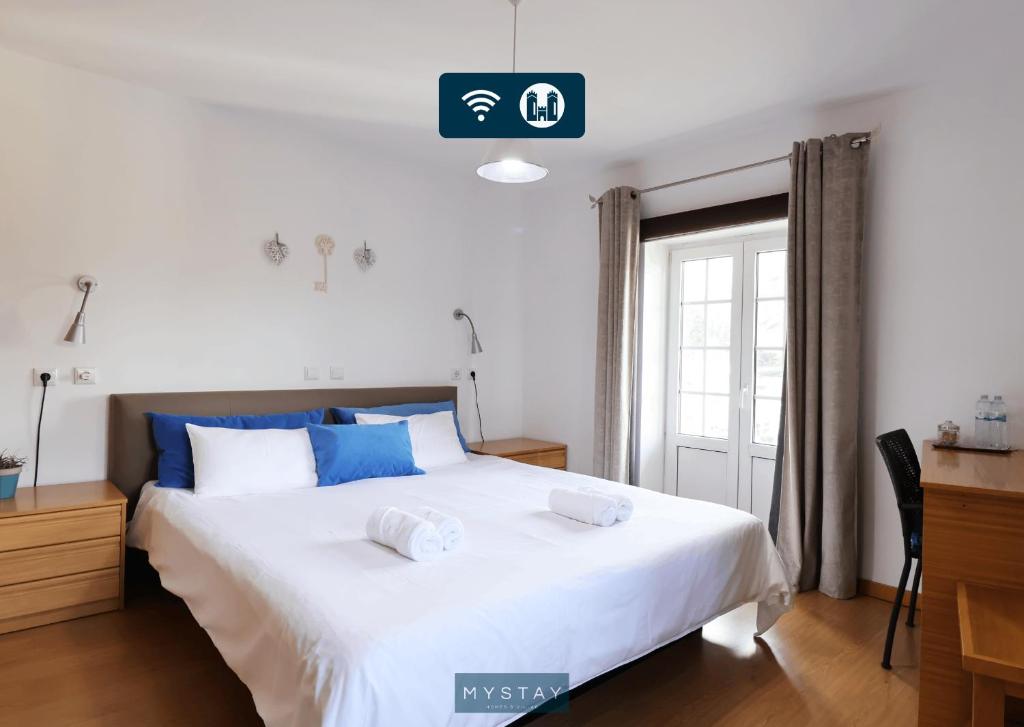 1 dormitorio con 1 cama blanca grande con almohadas azules en MyStay - Casa Miná, en Montalegre