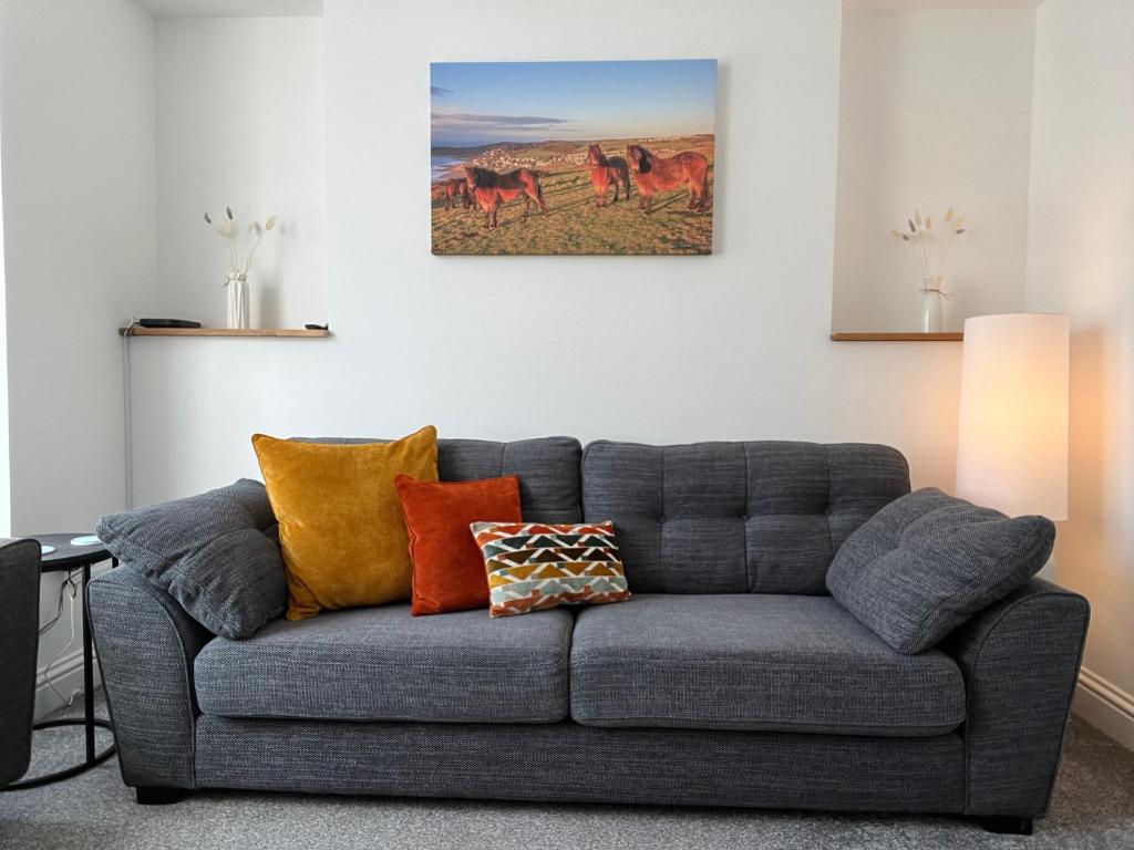 a living room with a gray couch with colorful pillows at Saltwater Pearl - A charming 4 bed townhouse in Ilfracombe