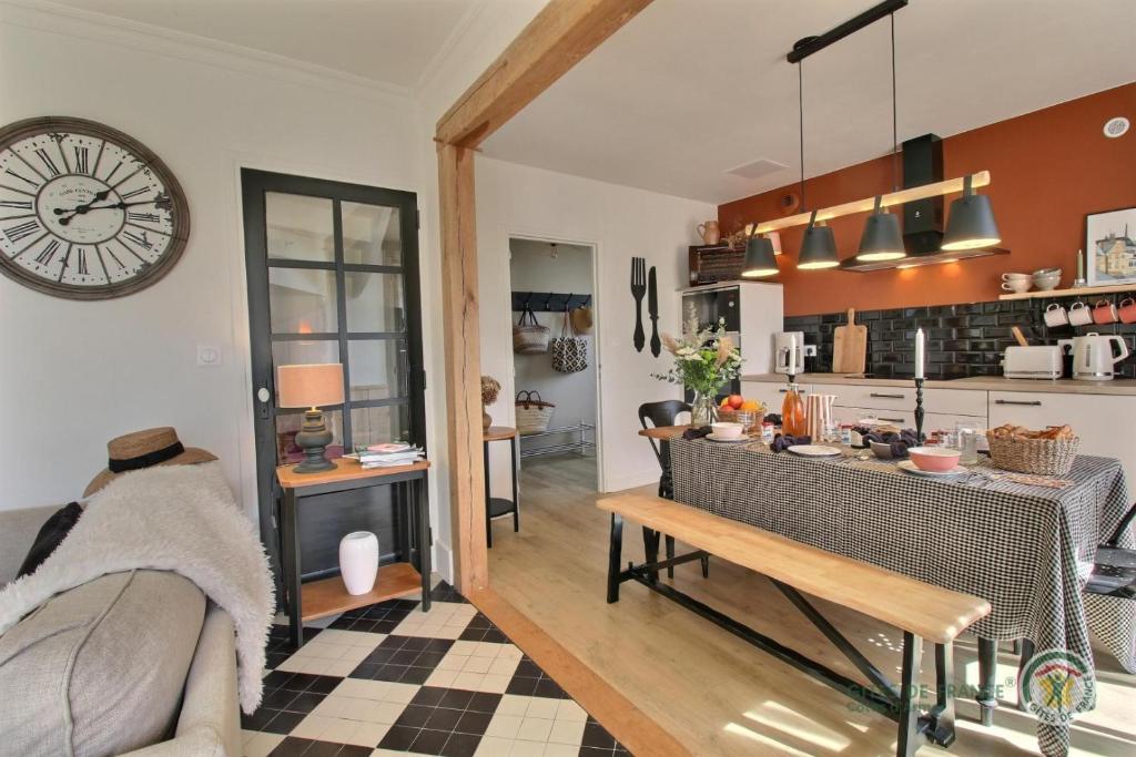 a kitchen and living room with a clock on the wall at Les pommettes in Plouër-sur-Rance