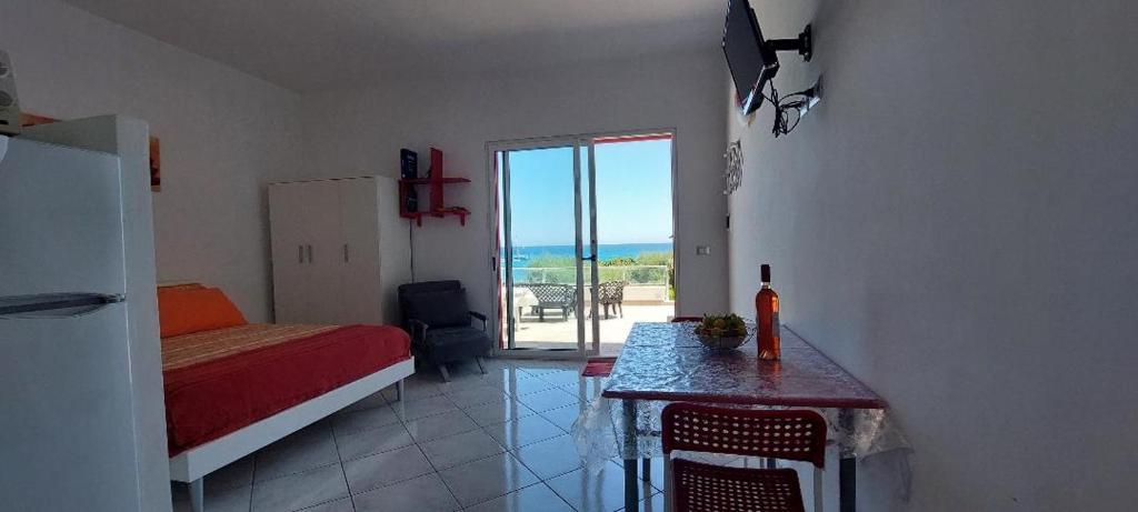 a bedroom with a bed and a table with a view at Monolocale sul Lungomare San Foca in San Foca