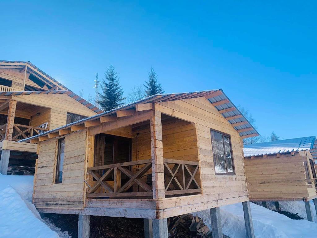 una cabaña de madera en la nieve con nieve en MESTIA COTTAGE TiME, en Mestia